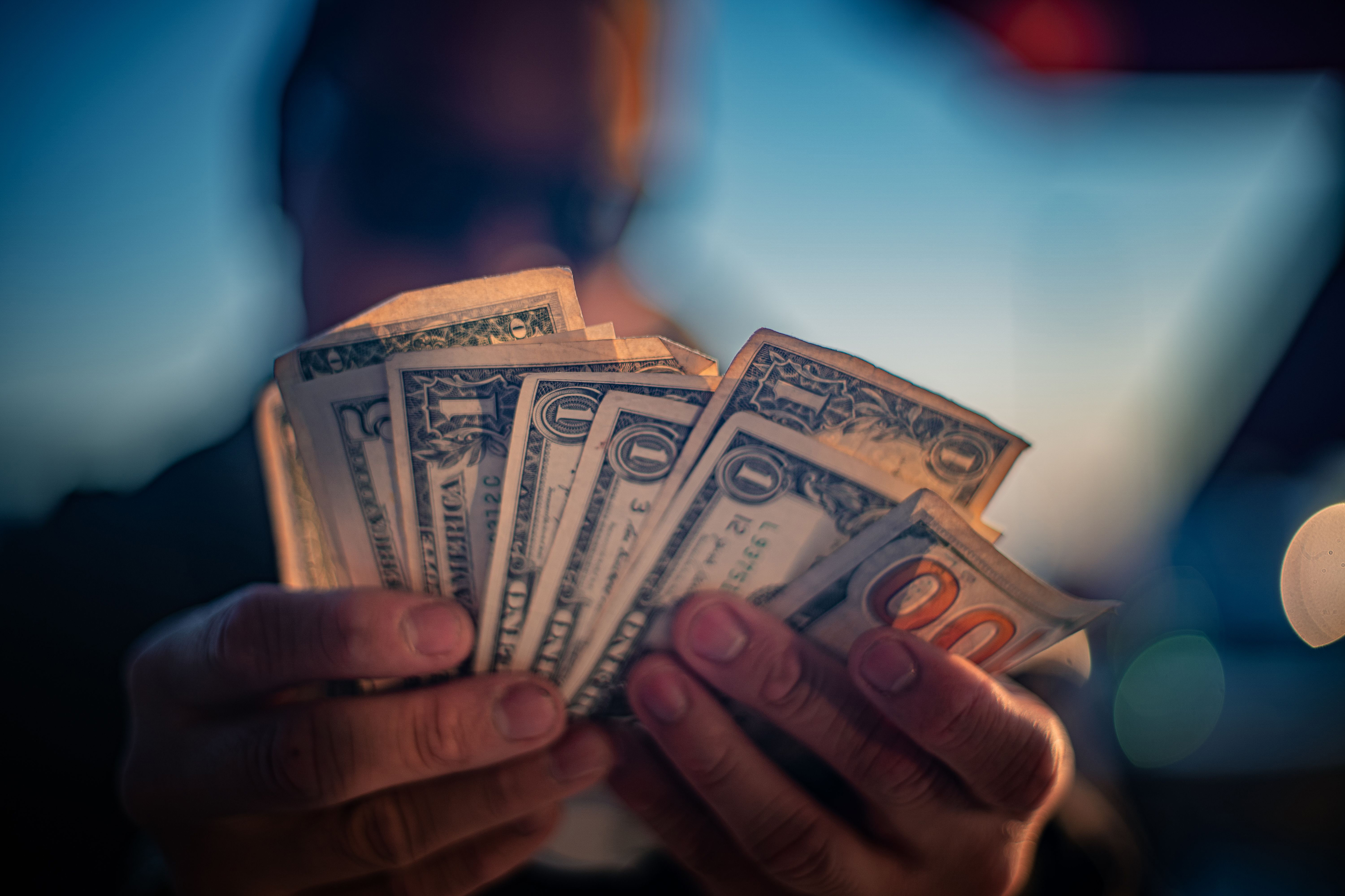 Man holding a bunch of money in his hands with a blurry background